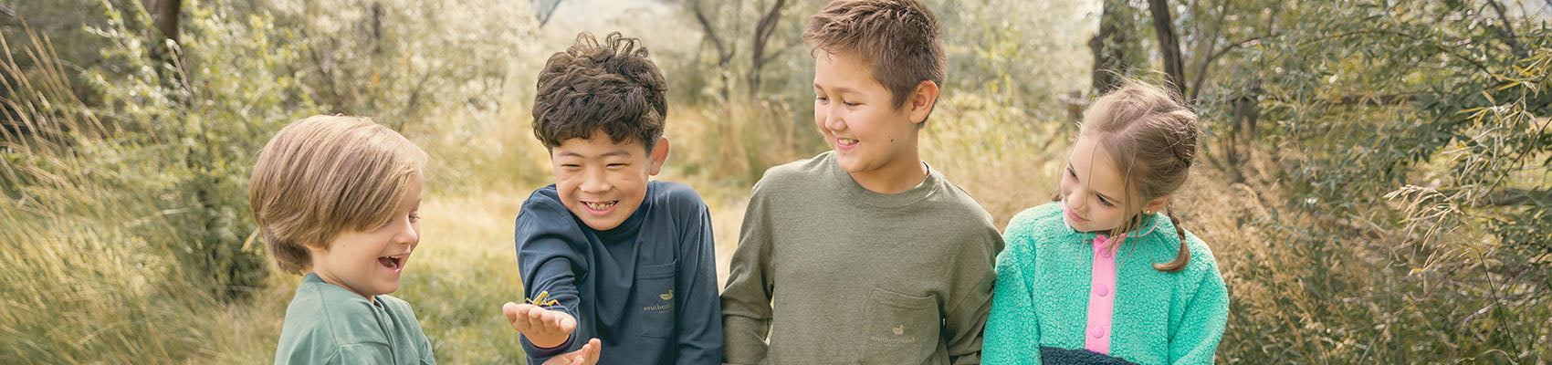 Two kids play on a beachside boardwalk wearing Columbia kids apparel.