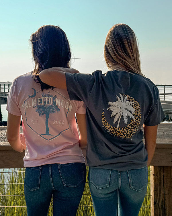 two women standing on a pier wearing palmetto moon t-shirts
